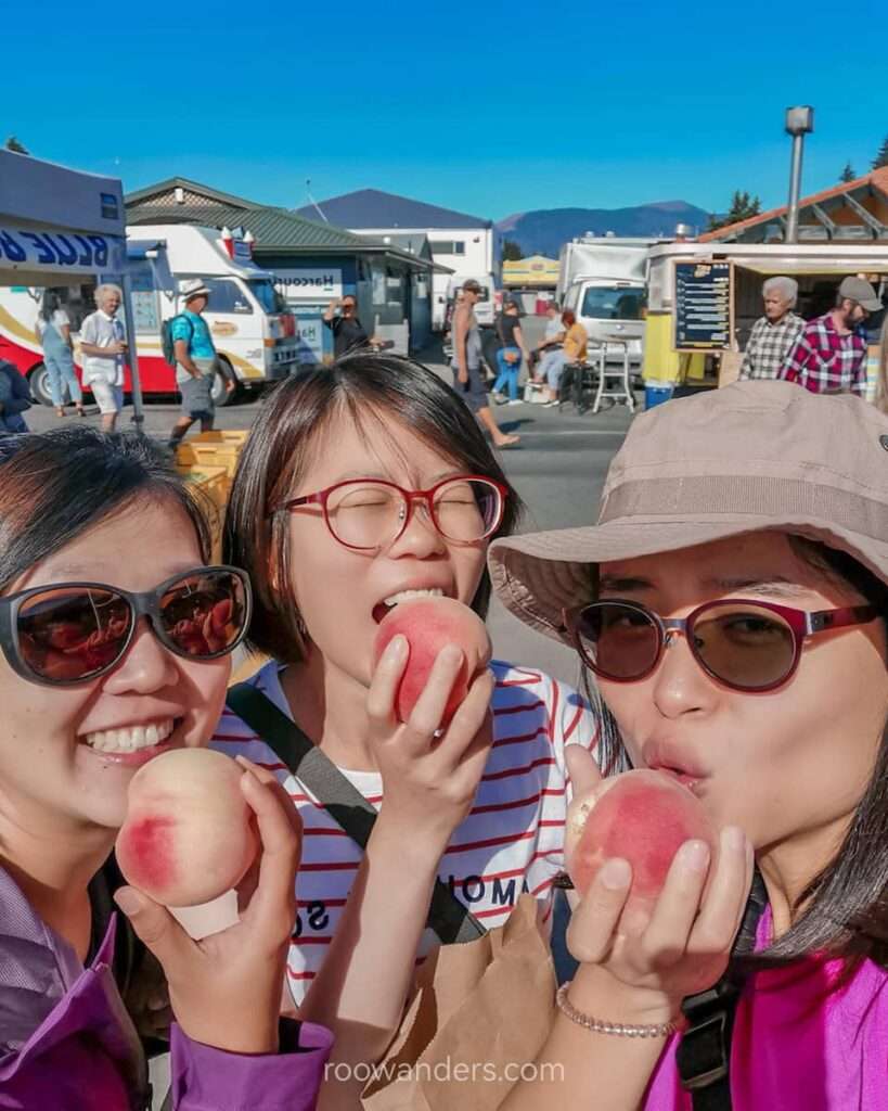 Enjoying a peach at Motueka Farmers' Market, New Zealand - RooWanders